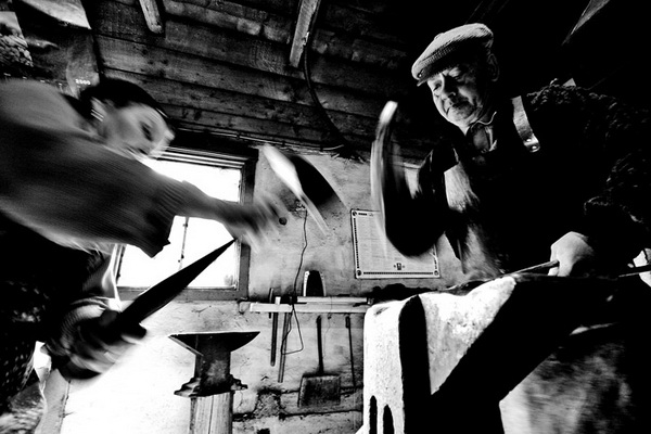 Two men working over the anvil