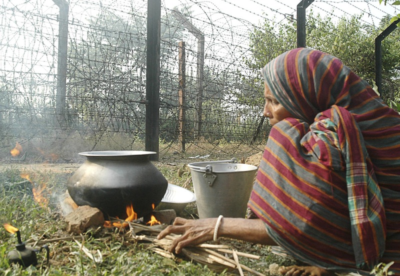 Woman prepares food infront of international border fencing at Lankamura village of South Tripura
