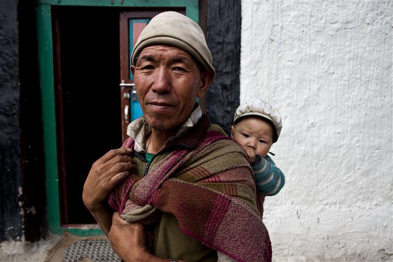 An old Loba man holds her grandson and poses for a picture .