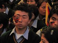 Young Tibetan boy sketches his face with Tibetan Flag.